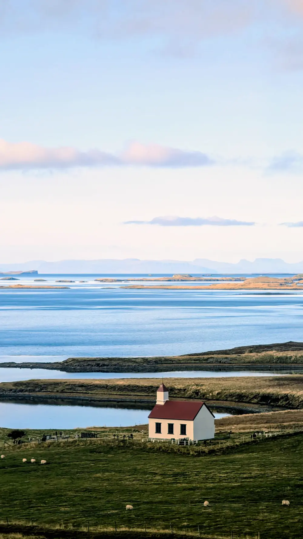 A red-roofed church beside a still loch at dawn