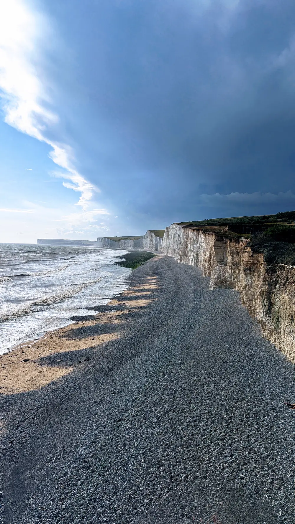 Chalk cliffs and a pebble beach under a dark storm front